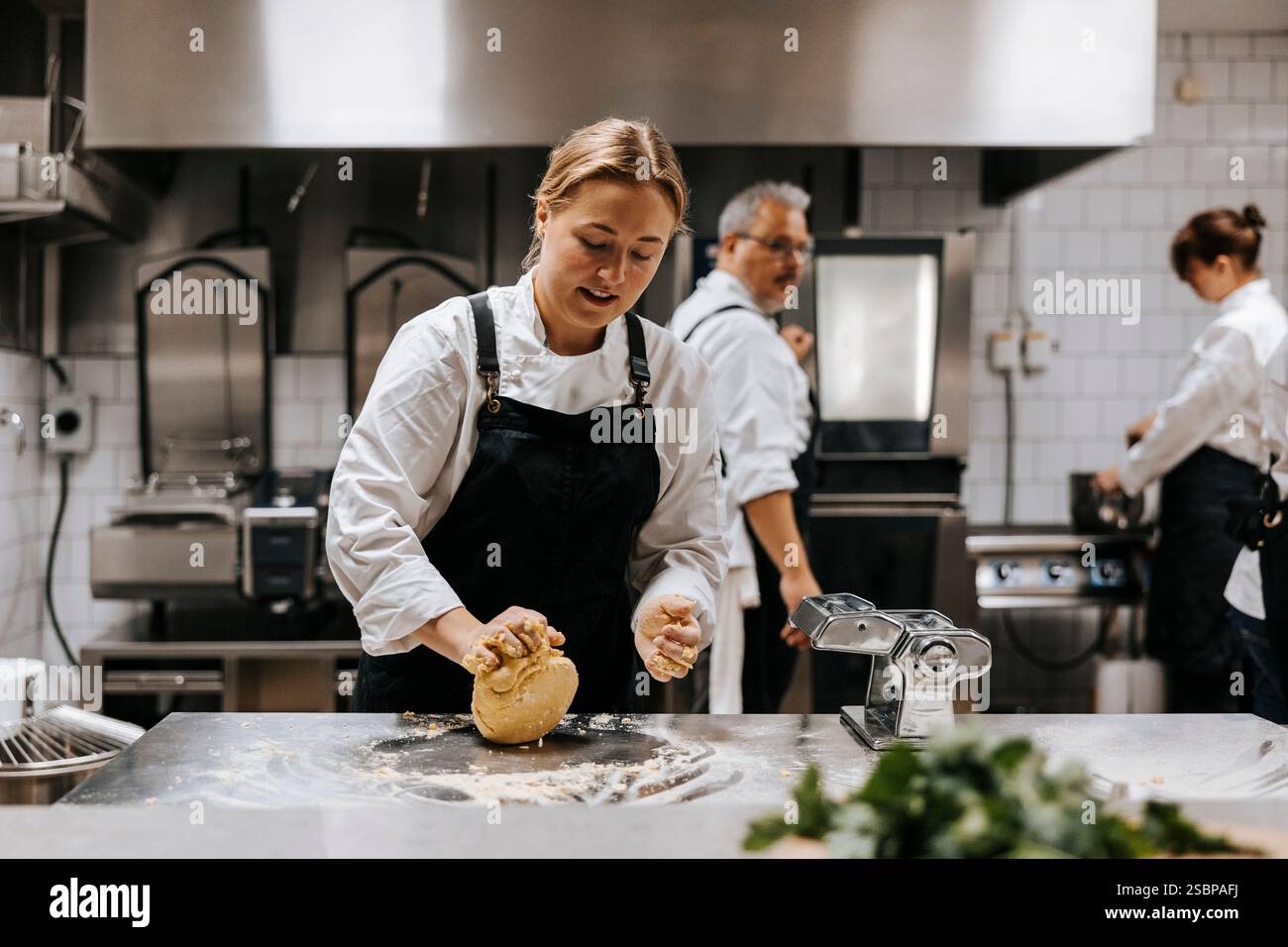 Una giovane chef che impastava l'impasto sul bancone della cucina del ristorante Foto Stock