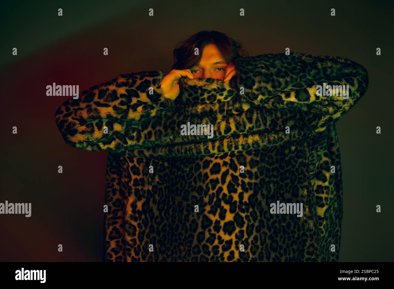 Un giovane uomo si avvolge in un cappotto oversize con stampa leopardata, che irradia sicurezza e stile. Foto Stock