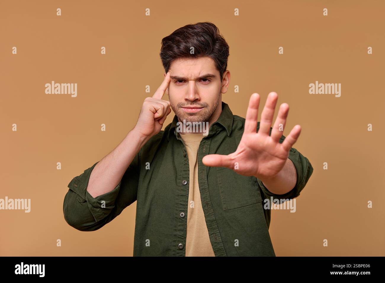 Un giovane si esprime con sicurezza, usando una mano per gesti toccando leggermente il tempio, mostrando un pensiero e una contemplazione Foto Stock