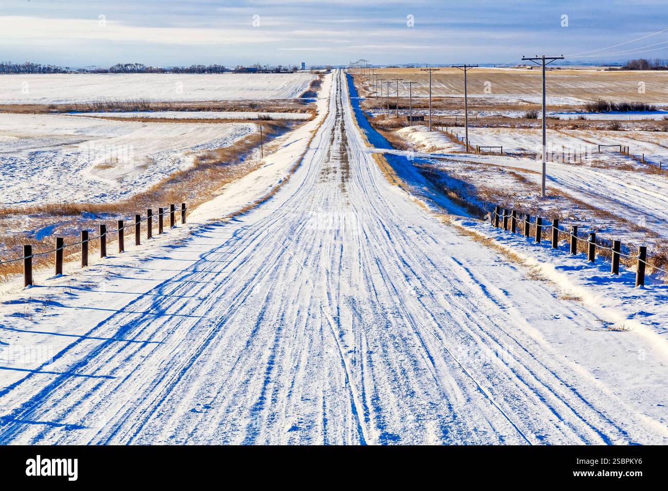 Strada innevata con molta neve sul terreno. La strada è lunga e dritta Foto Stock