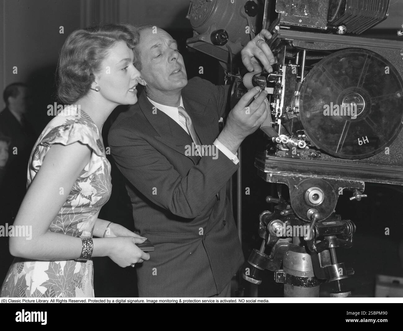 Haide Göransson , 1928-2008 , attrice e modella svedese. Qui in uno studio cinematografico durante una ripresa cinematografica, dove guarda con interesse come una macchina fotografica è piena di film. La pellicola è costituita da un materiale di base, solitamente acetato di cellulosa o precedentemente cellulosa nitrata (chiamata anche celluloide), che è rivestito con un materiale fotosensibile, di solito alogenuri d'argento (come il bromuro d'argento o il cloruro d'argento), incorporato in un'emulsione di gelatina. Svezia 1949 Foto Stock