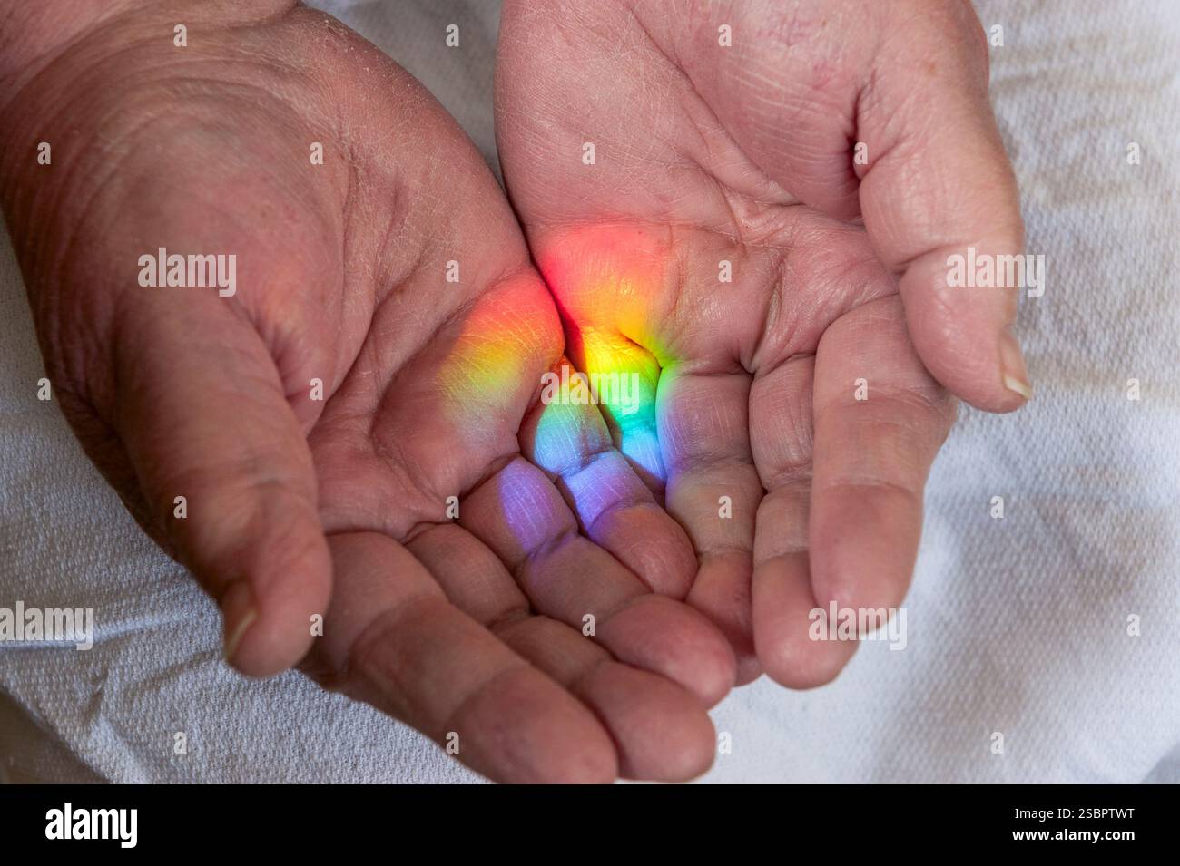 Un vero arcobaleno spettrale sulla mano aperta di una donna, gettato da un prisma appeso in una finestra esposta a sud esposta alla luce del sole. Foto Stock
