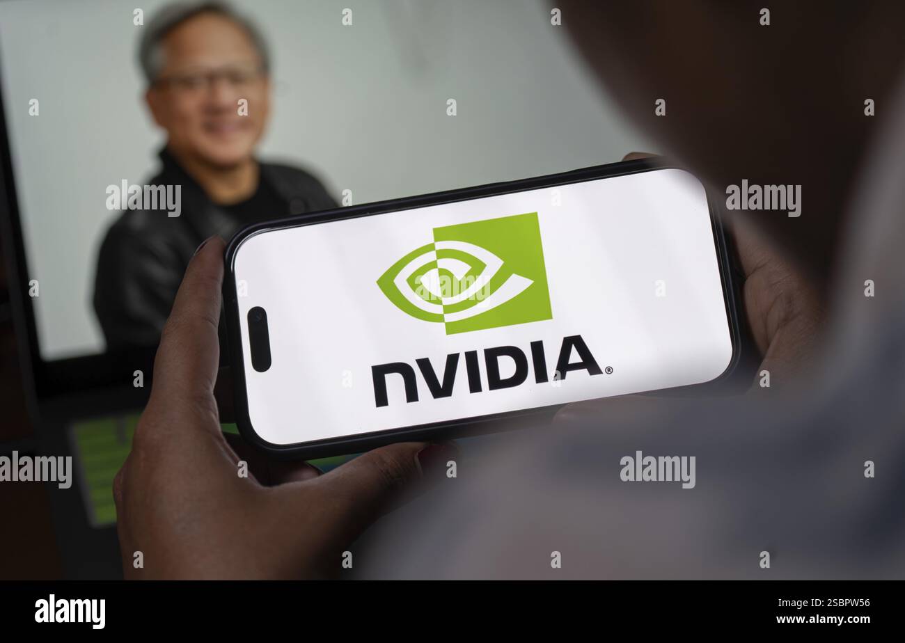 In questa illustrazione fotografica, il logo Nvidia Corporation viene visualizzato su uno schermo iPhone davanti alla foto del CEO di Nvidia Jensen Huang su Jan Foto Stock