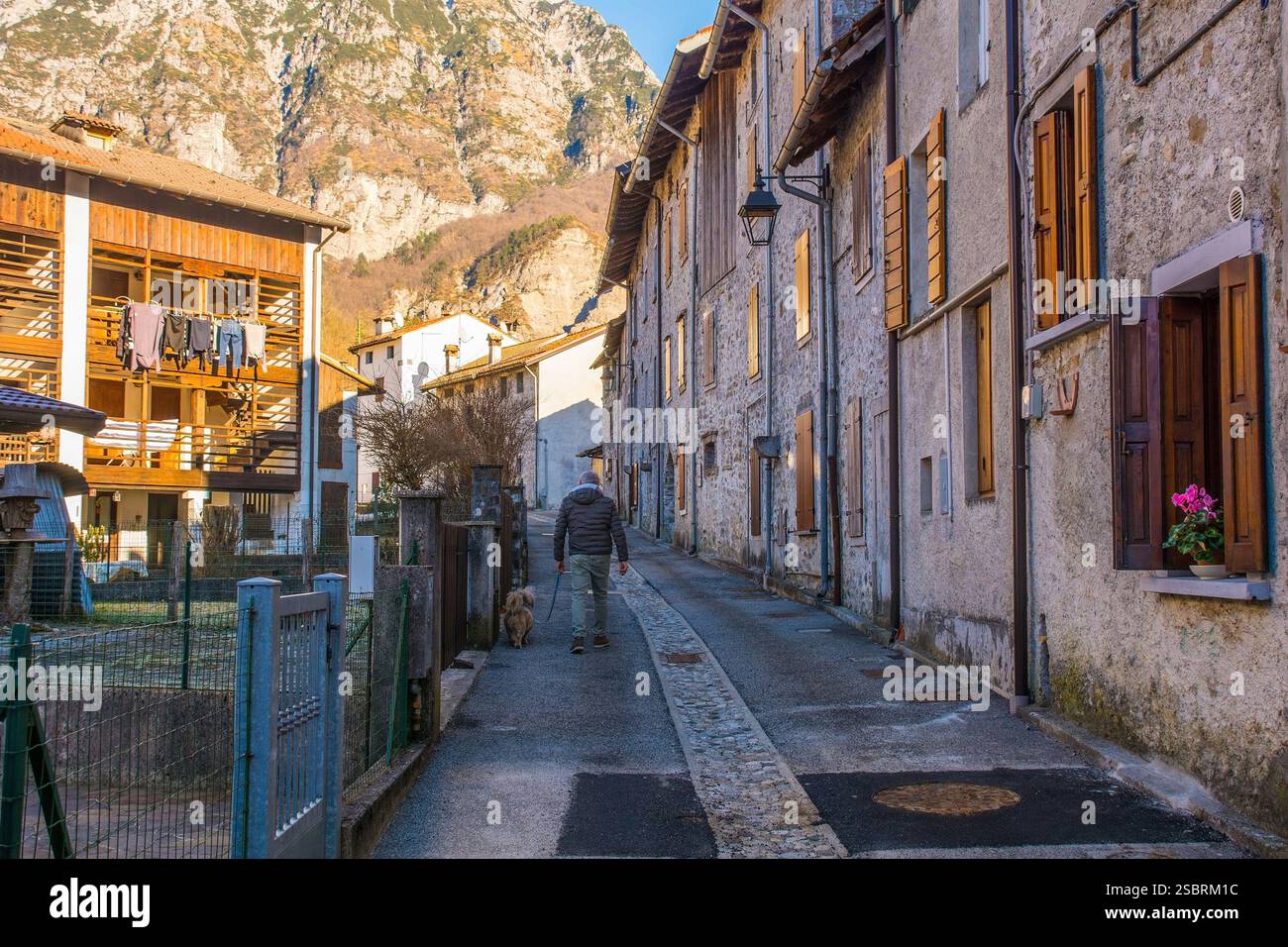 Un uomo anziano cammina il suo cane lungo un vicolo tranquillo nel villaggio storico di Andreis. Provincia di Pordenone, Friuli-Venezia Giulia, Italia nord-orientale. Foto Stock