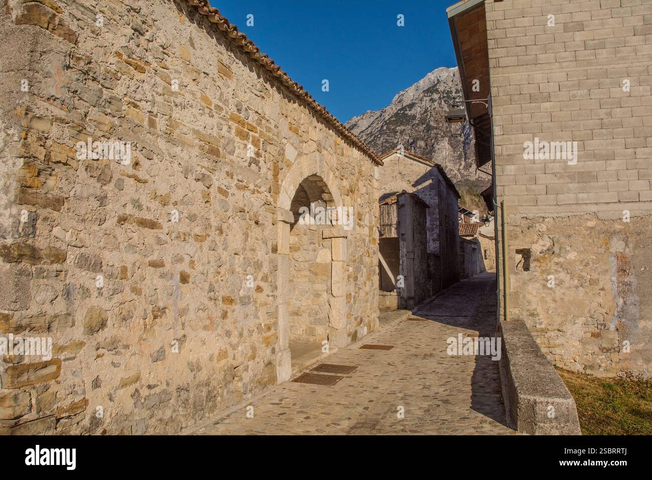 Un arco in una storica parete di pietra lungo una strada tranquilla nel villaggio storico di Andreis. Provincia di Pordenone, Friuli-Venezia Giulia, Italia nord-orientale. Foto Stock