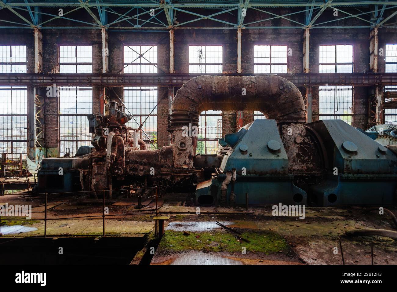 Generatore a turbina arrugginito. Abbandonati distrutti dalla guerra e cresciuti da piante e macchinari muschio della centrale Tkvarcheli Tquarchal, Abkhazia, Georgia. Foto Stock
