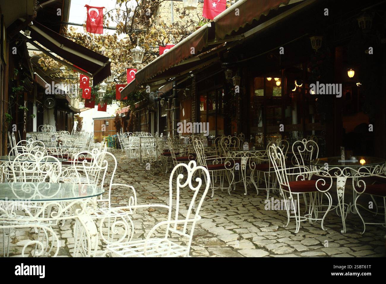Safranbolu, Karabük, Turchia – 28 novembre 2024 : Un cortile lastricato in pietra classico caffè all'aperto con eleganti sedie e tavoli in ferro battuto bianco Foto Stock