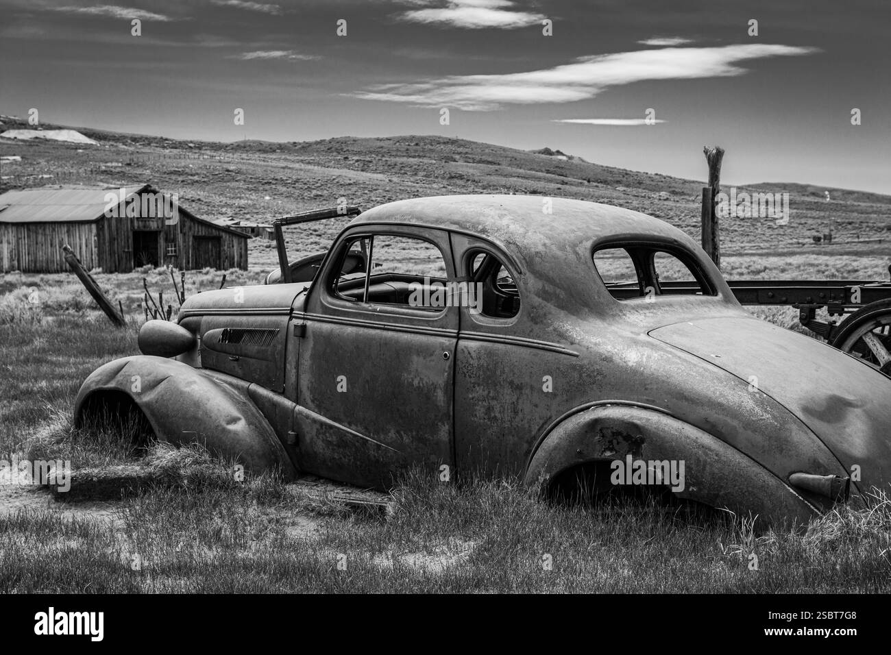 La vista laterale di una classica auto spazzatura abbandonata nella città fantasma di Bodie. Una coupé a due porte del 1937. Foto Stock