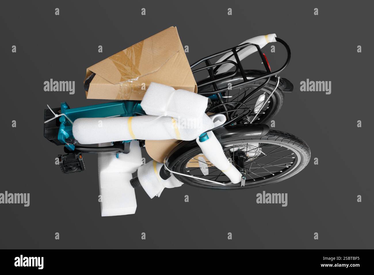 Una bici compatta è dotata di materiali protettivi e pronta per la spedizione. Gli articoli sono disposti in modo ordinato su uno sfondo grigio, a dimostrazione della loro r Foto Stock