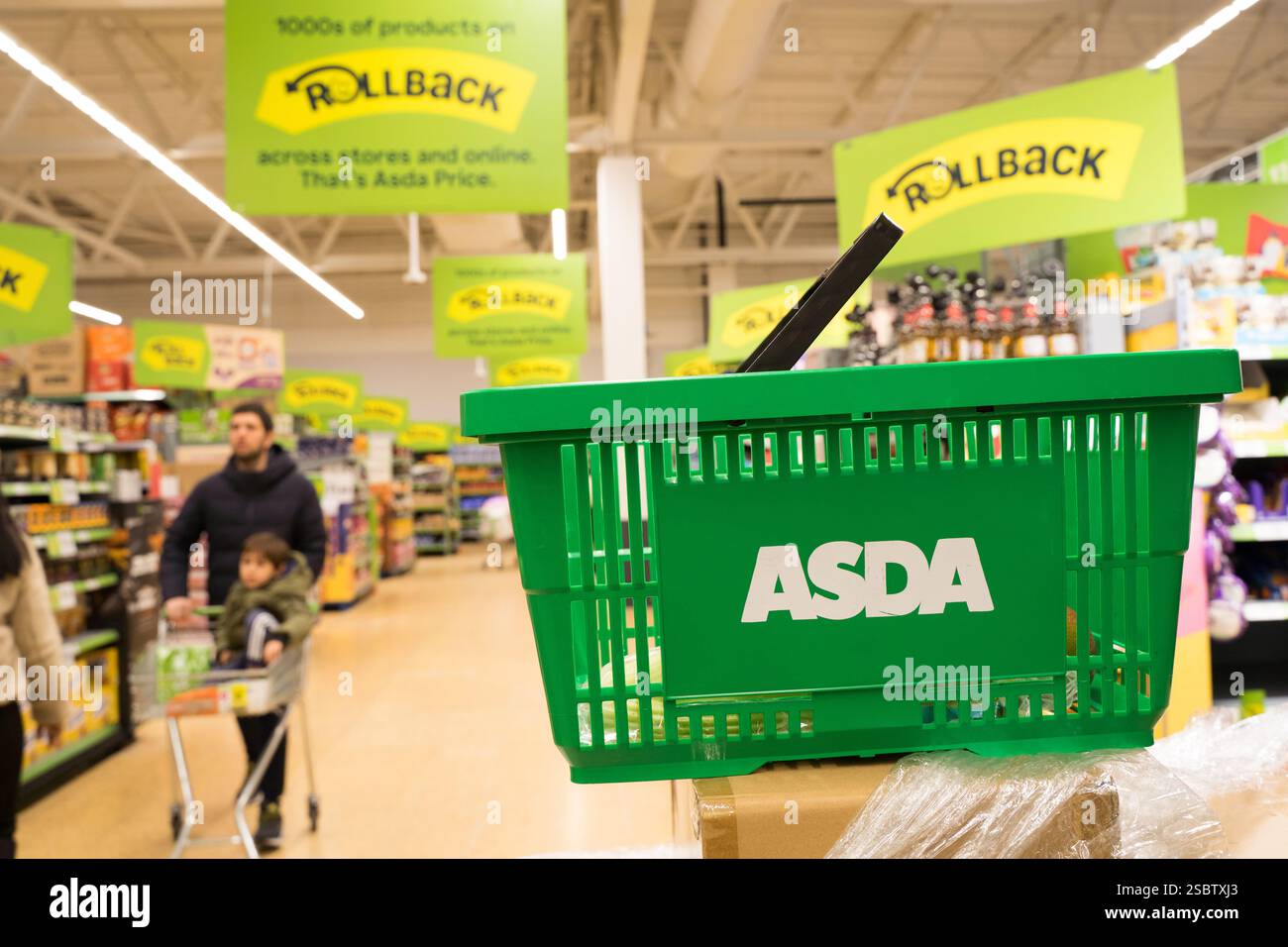 Carrello ASDA al centro del corridoio dello shopping pieno di poster Price Rollback presso l'ASDA Supermarket England UK Foto Stock