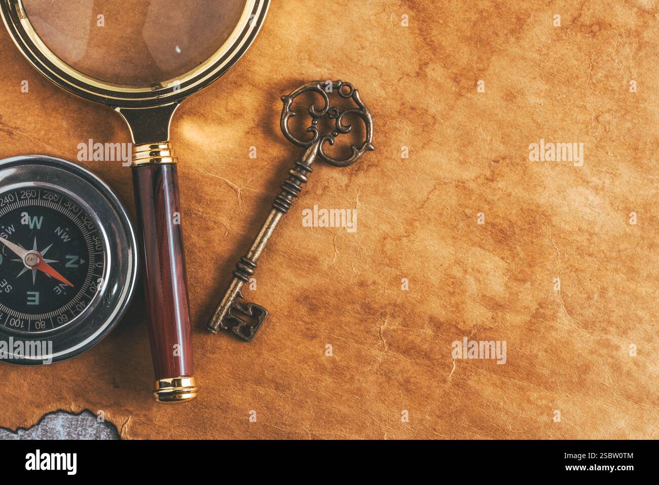 Lente d'ingrandimento vintage, bussola e vecchia chiave su vecchio sfondo di carta Foto Stock