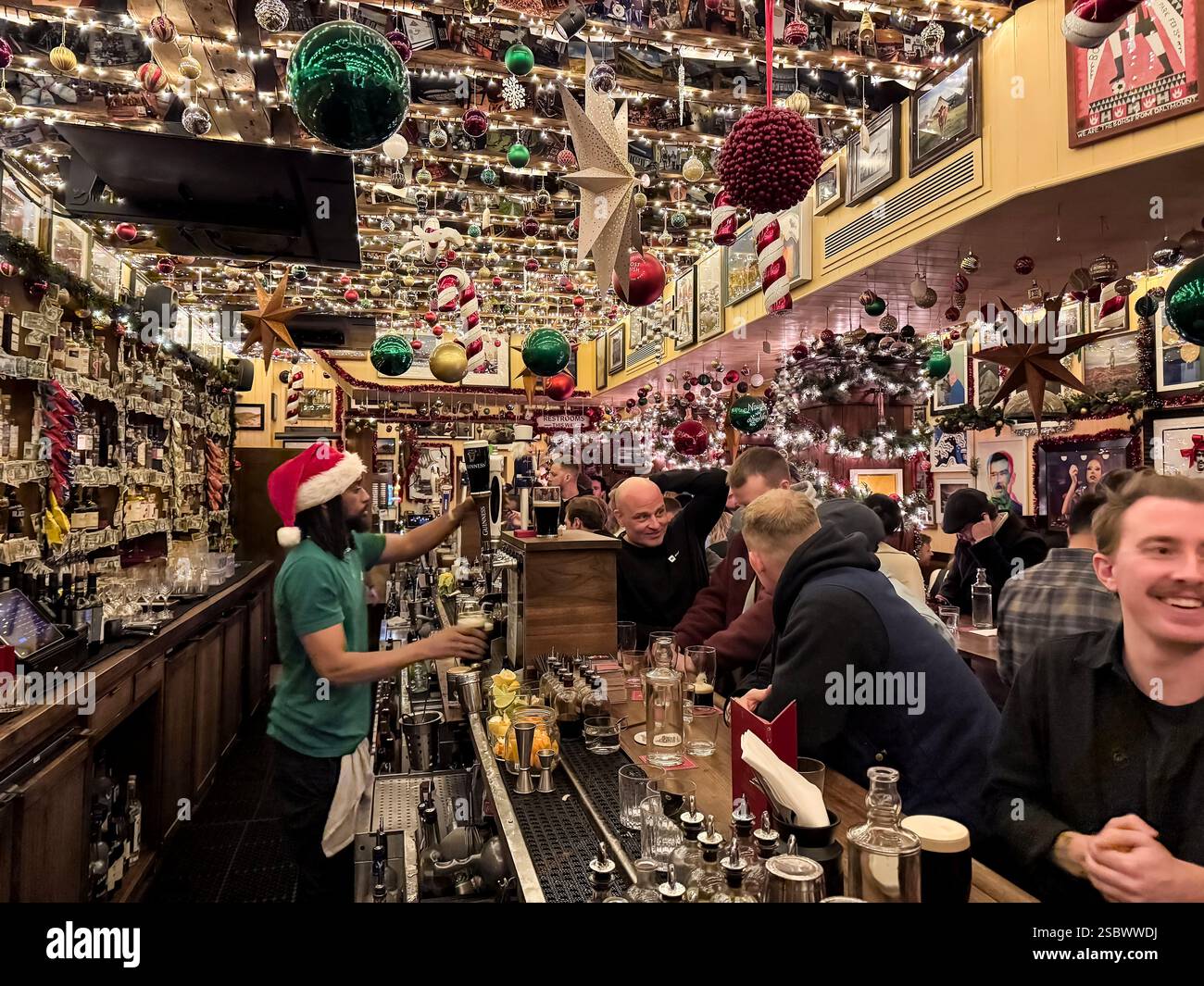 I clienti si divertono, chiacchierano, gustando pinte di birra e cocktail al Dead Rabbit in Water Street nel centro di Manhattan, New York, USA Foto Stock