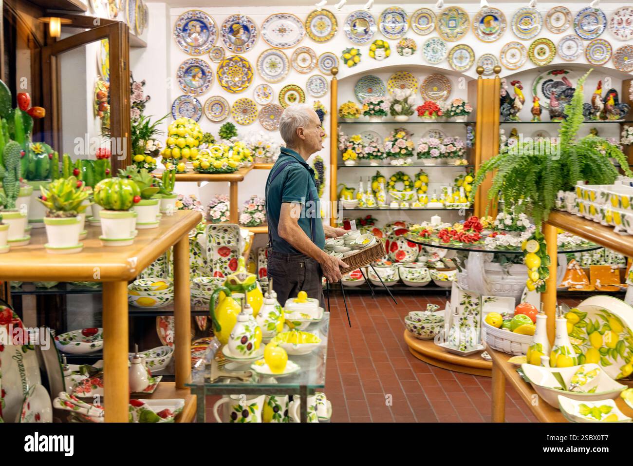 Sirmione, Italia - 21 settembre 2024: Un negoziante che organizza ceramiche italiane artigianali in un negozio di ceramica tradizionale Foto Stock