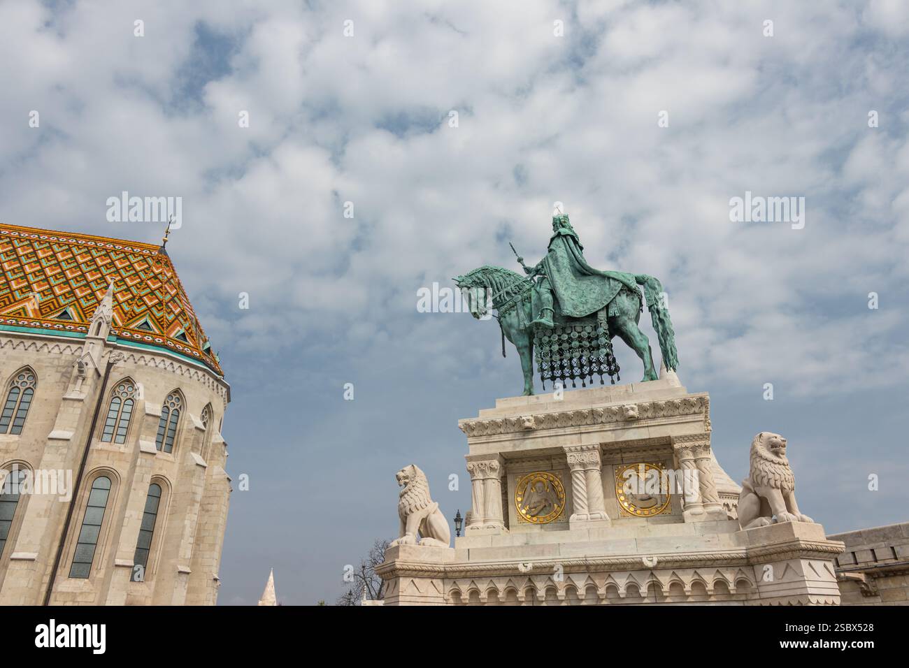 Una scultura storica raffigurante una figura montata su una base decorata, fiancheggiata da statue di leoni, adagiata contro un cielo parzialmente nuvoloso. L'intricato artigiano Foto Stock