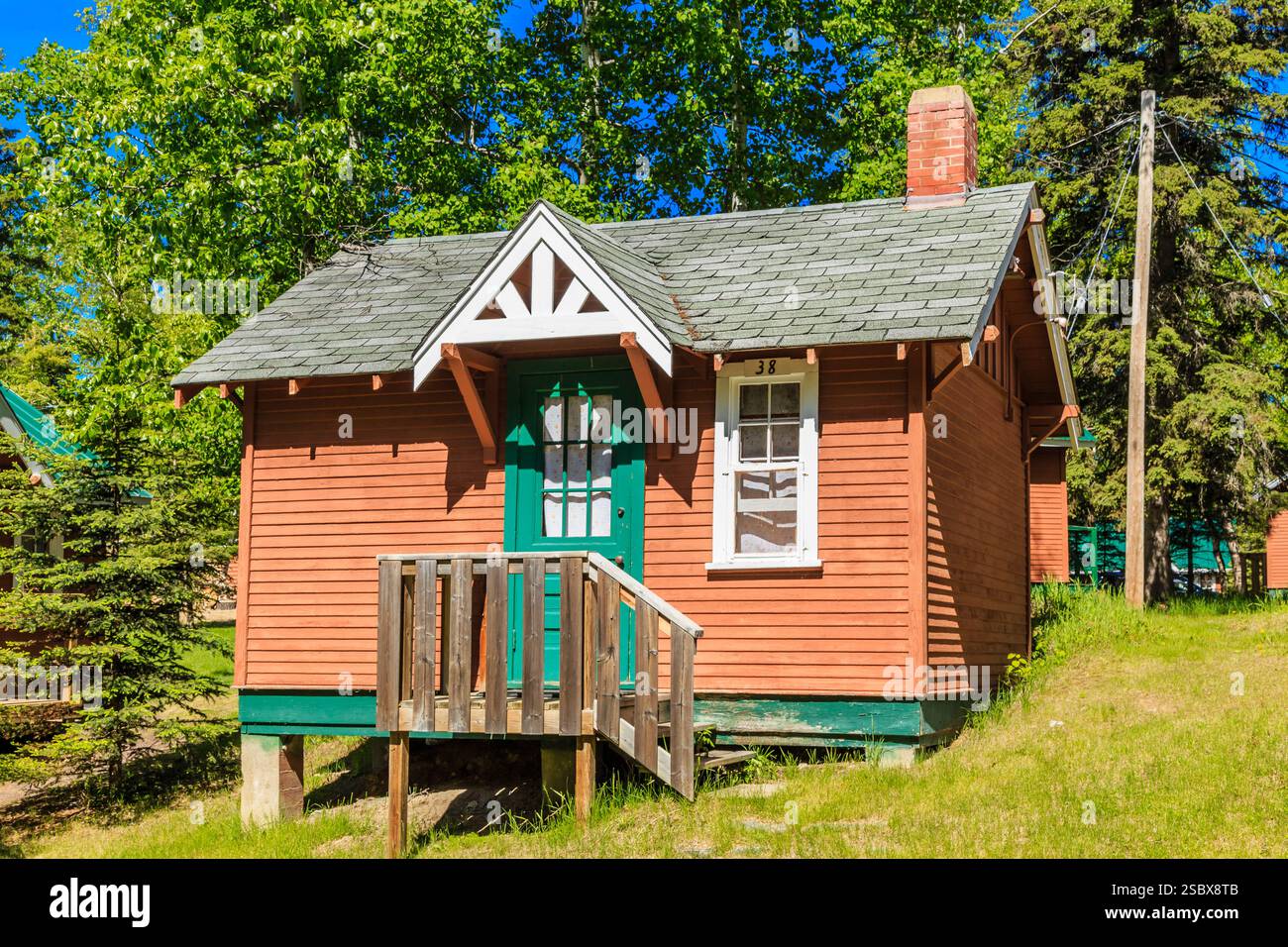 Piccola casa rossa con una porta verde e una finestra bianca. La casa è su una collina Foto Stock
