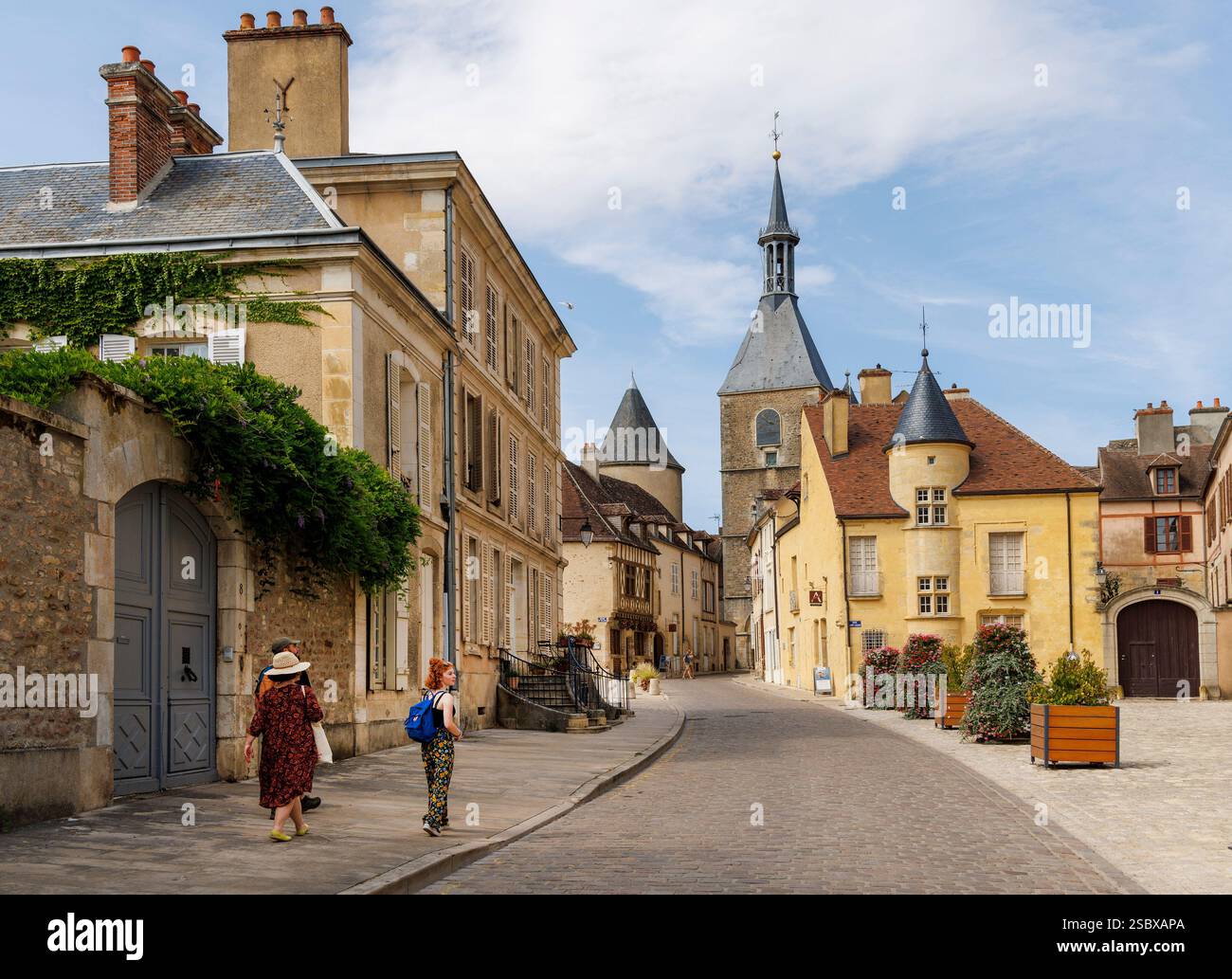 Persone che camminano per strade tranquille con la torre dell'orologio in lontananza, Avallon, Yonne, Burgandy, Bourgogne-Franca Contea, Francia Foto Stock
