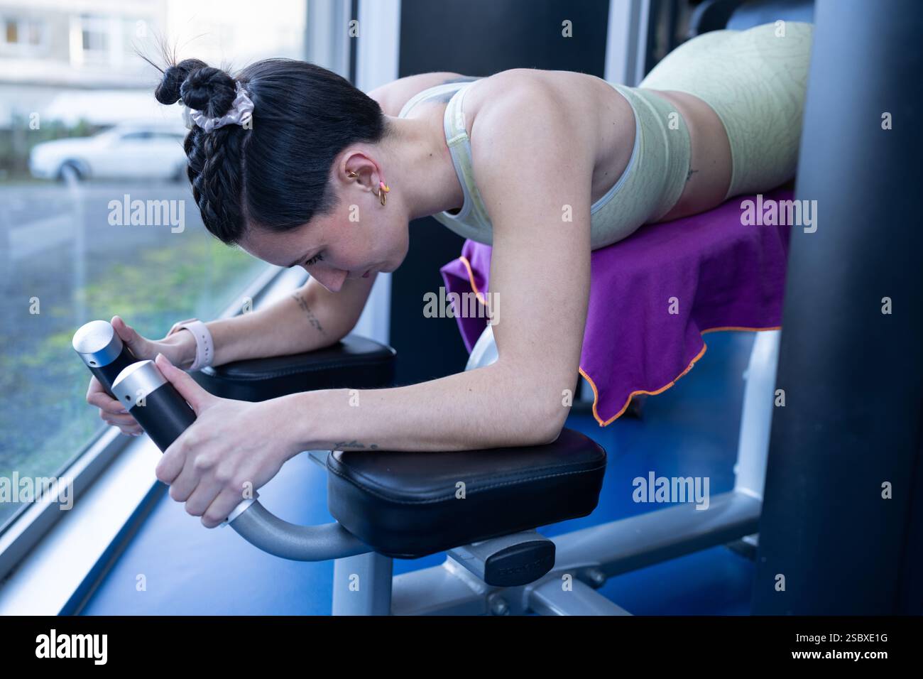 Atleta concentrata che rafforza i muscoli della schiena utilizzando la macchina di iperestensione nel moderno centro fitness, promuovendo uno stile di vita sano e fisico noi Foto Stock