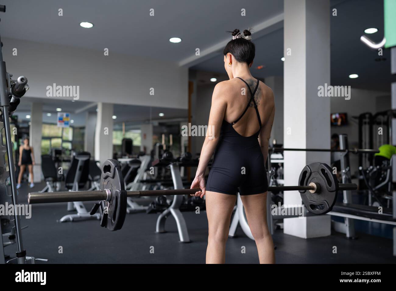 Forte atleta femminile che esegue deadlift con un barbell, mostrando la sua dedizione e forza in un centro fitness ben attrezzato, ispirando una guarigione Foto Stock
