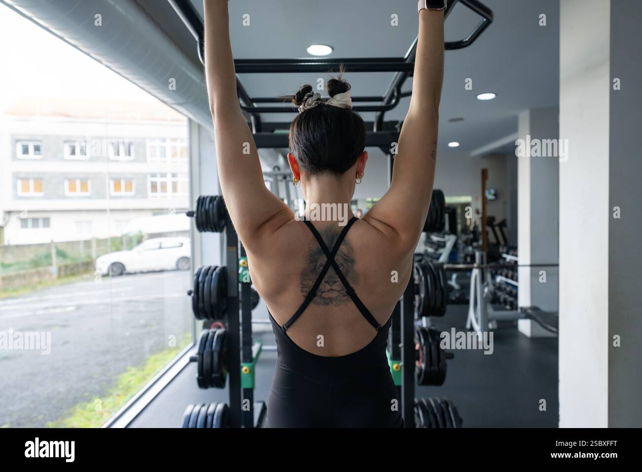 Forte atleta che esegue esercizi di pull-up, dimostrando i suoi potenti muscoli della schiena in una moderna palestra, dimostrando dedizione al fitness Foto Stock