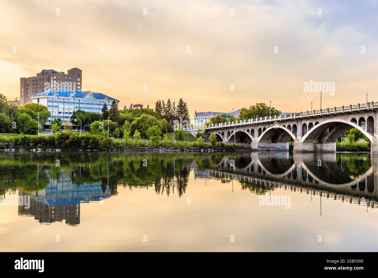 Ponte su un fiume con un riflesso di un edificio nell'acqua. Il ponte è sullo sfondo e l'edificio è in primo piano Foto Stock