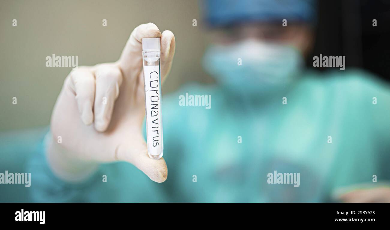 Mano con guanti e provetta etichettata coronavirus in un contesto medico Foto Stock