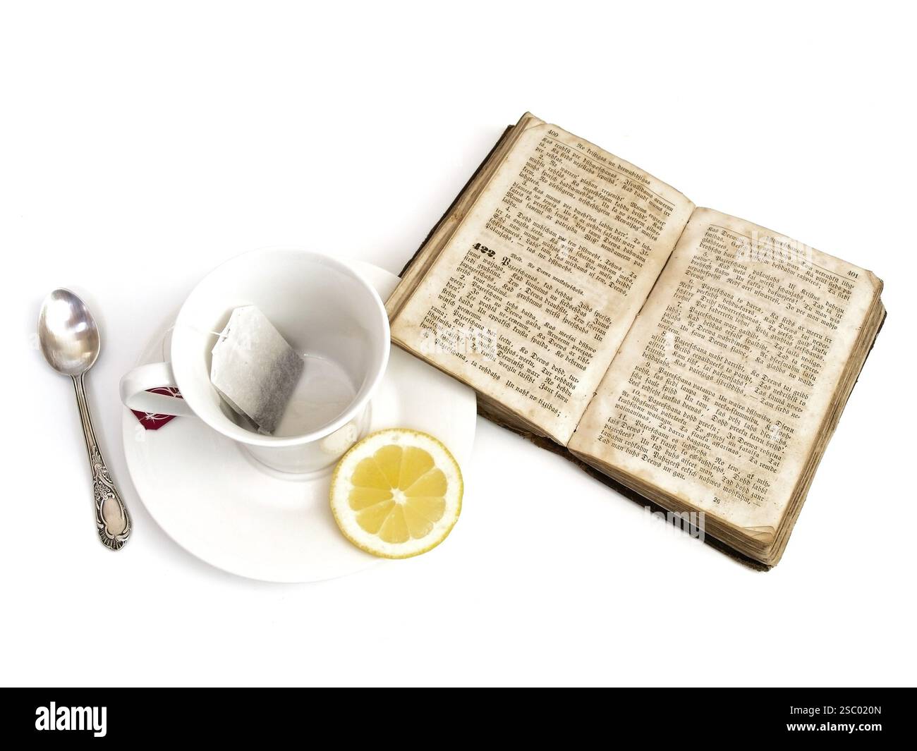 Tazza con teabag e limone vicino al vecchio libro aperto con Foto Stock