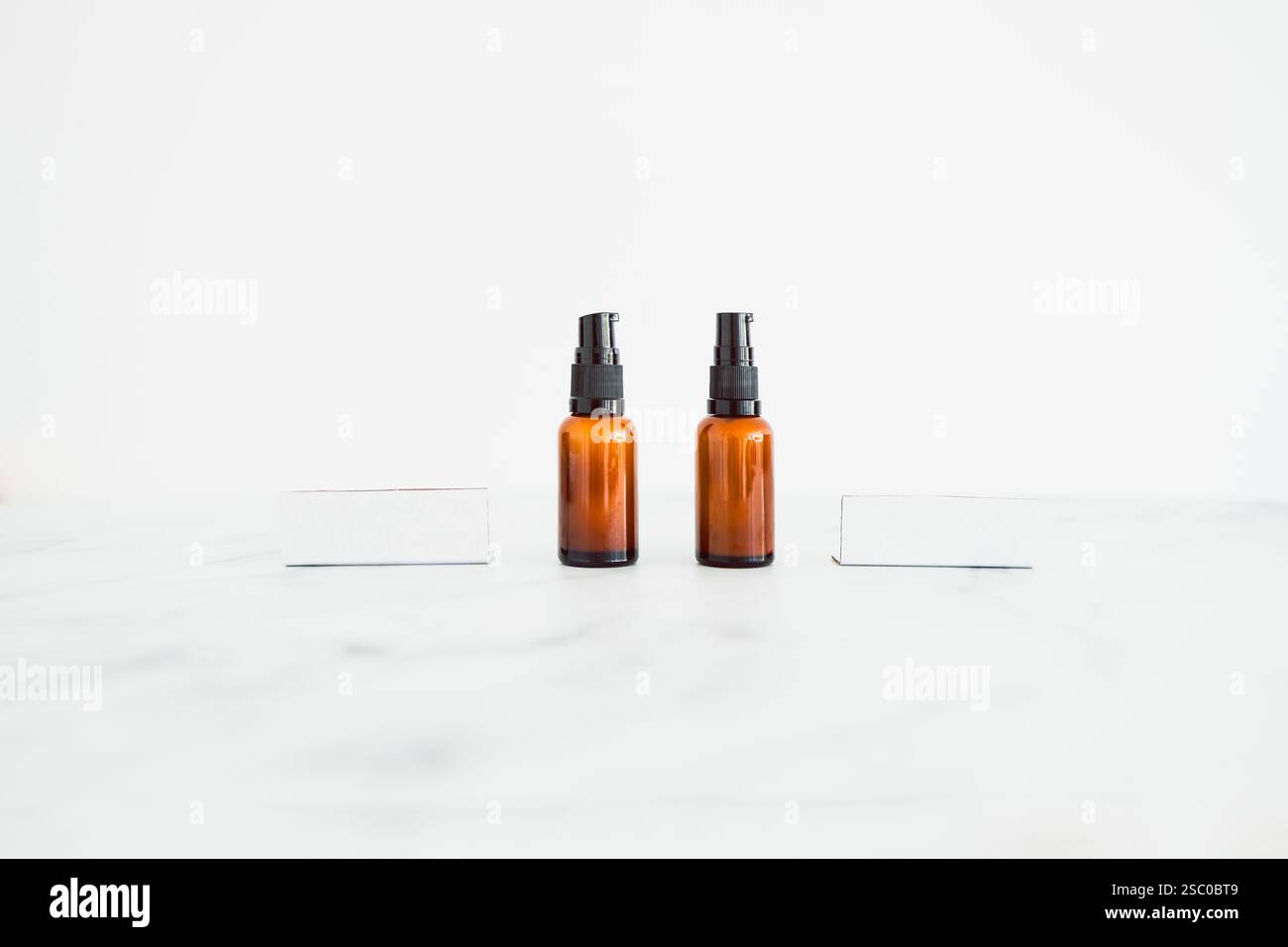 flaconi idratanti apothecary color ambra accanto a etichette vuote con spazio di copia su sfondo minimalista in marmo bianco Foto Stock flaconi idratanti apothecary color ambra accanto a etichette vuote con spazio di copia su sfondo minimalista in marmo bianco Foto Stock