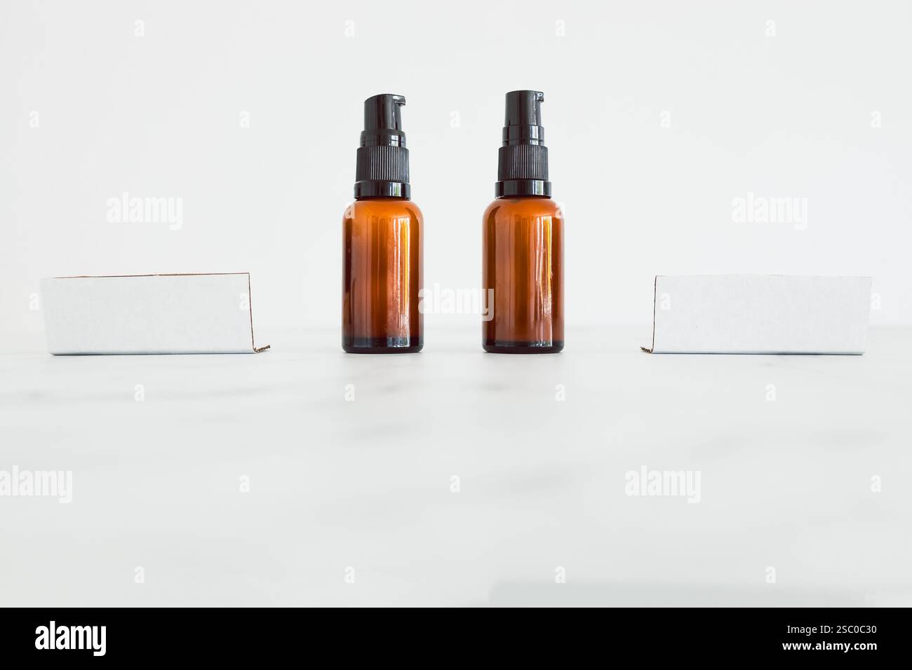 flaconi idratanti apothecary color ambra accanto a etichette vuote con spazio di copia su sfondo minimalista in marmo bianco Foto Stock flaconi idratanti apothecary color ambra accanto a etichette vuote con spazio di copia su sfondo minimalista in marmo bianco Foto Stock