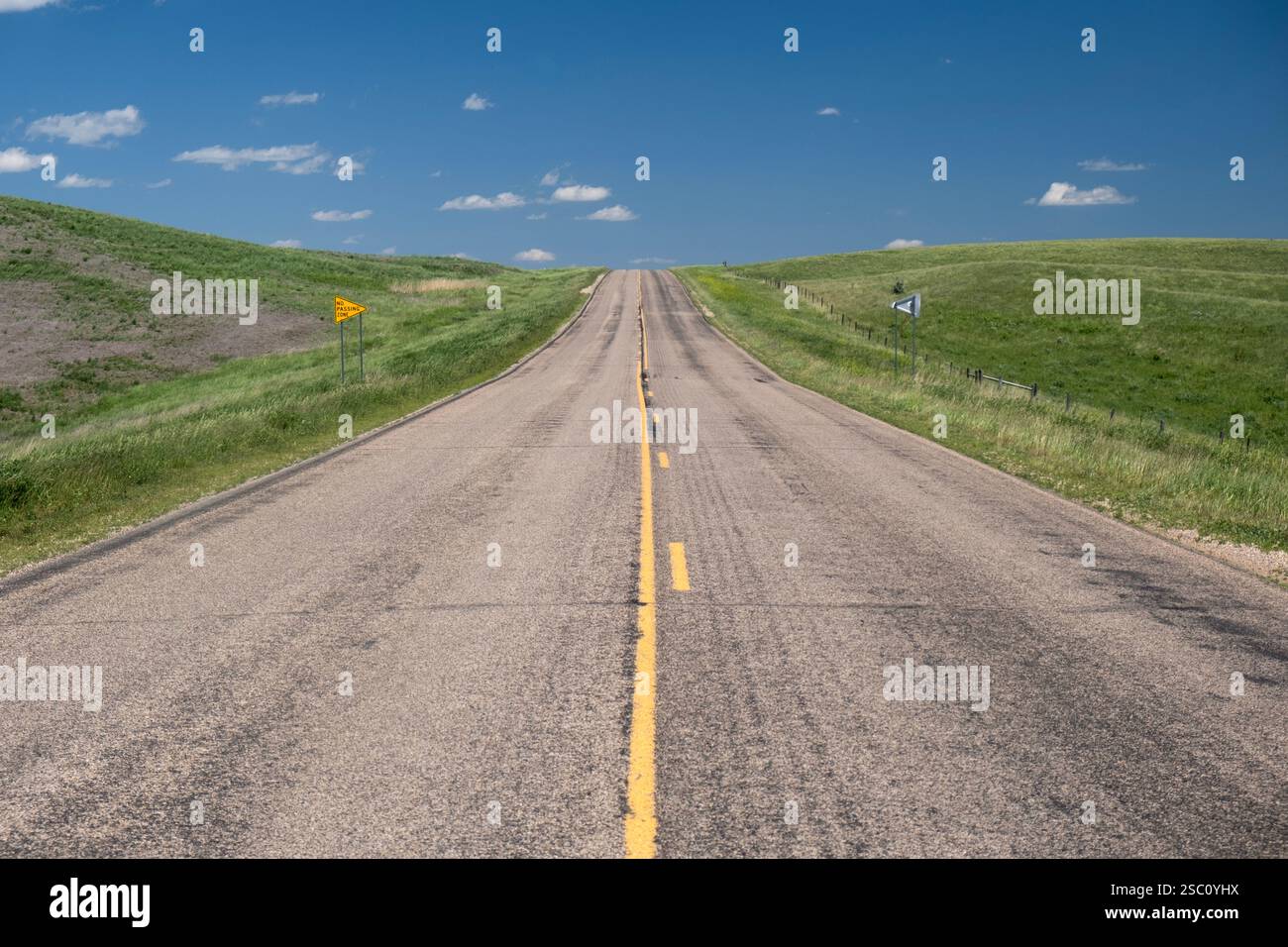 Tratto di autostrada solitario che si avvicina a una collina senza zone di passaggio sulle alte pianure di Day County, South Dakota Foto Stock