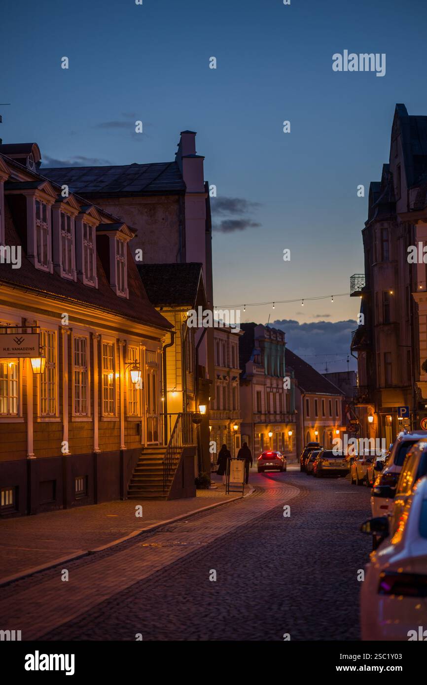 Affascinante scena di strada a Cesis, Lettonia al crepuscolo. Edifici storici con luci calde creano un'atmosfera accogliente in questa città vecchia. Perfetto per i viaggi, Foto Stock