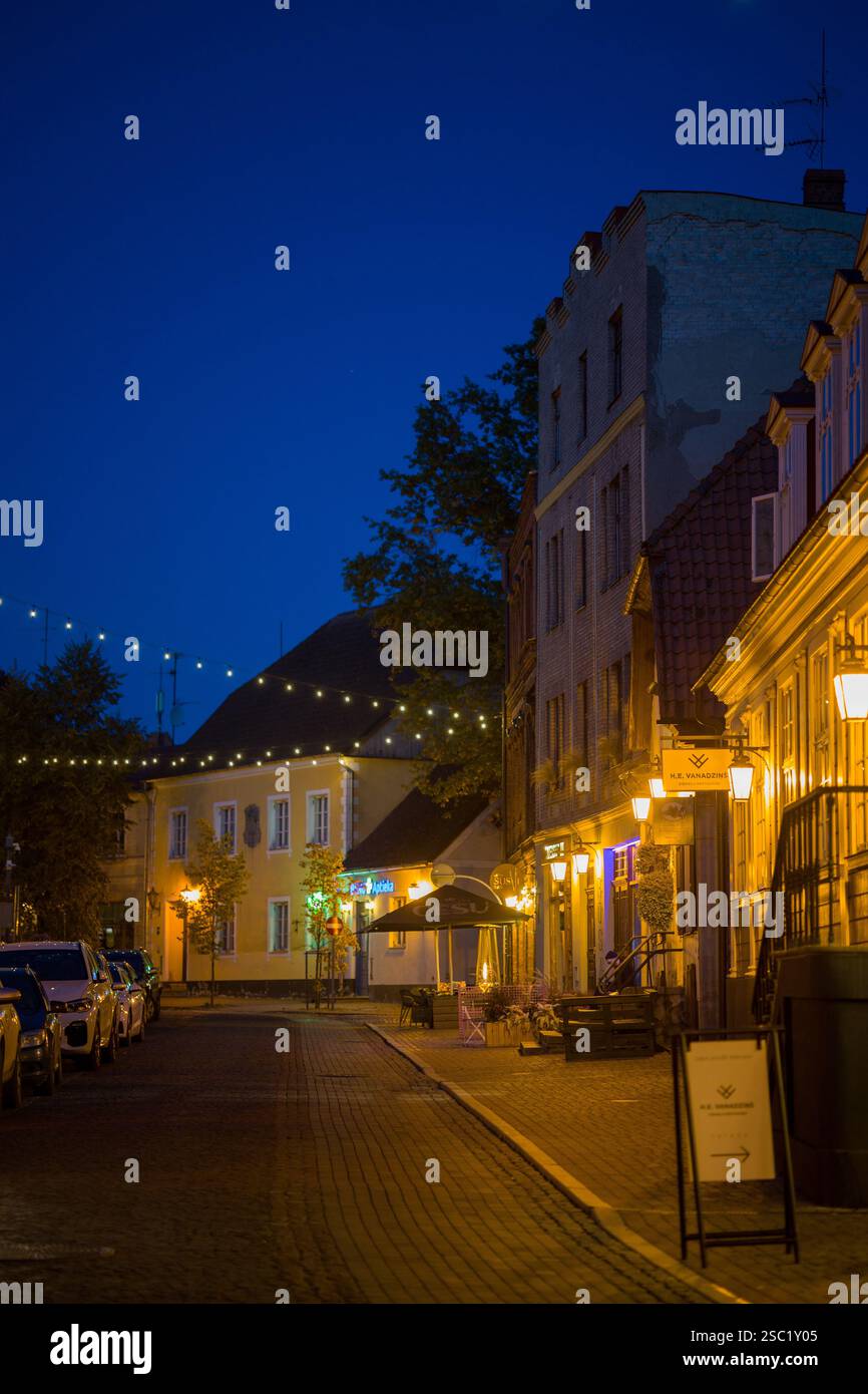 Affascinante scena di strada a Cesis, Lettonia al crepuscolo. Edifici storici con luci calde creano un'atmosfera accogliente in questa città vecchia. Perfetto per i viaggi, Foto Stock