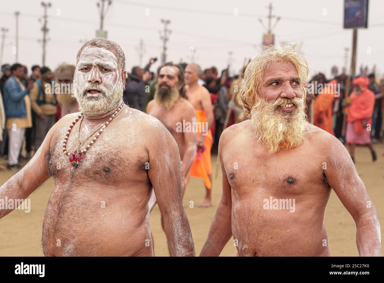 Due Naga Sadhus condividono un momento di gioia, i loro volti brillano di felicità dopo aver completato il loro bagno sacro, incarnando la pace e la realizzazione spirituale. Foto Stock