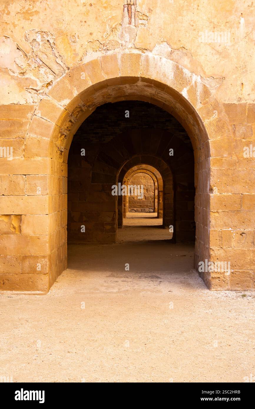 Una vista ipnotizzante di una serie di archi nel Castello di Maniace, Siracusa, con ombre sorprendenti che creano profondità e contrasto contro l'antico arco in pietra Foto Stock