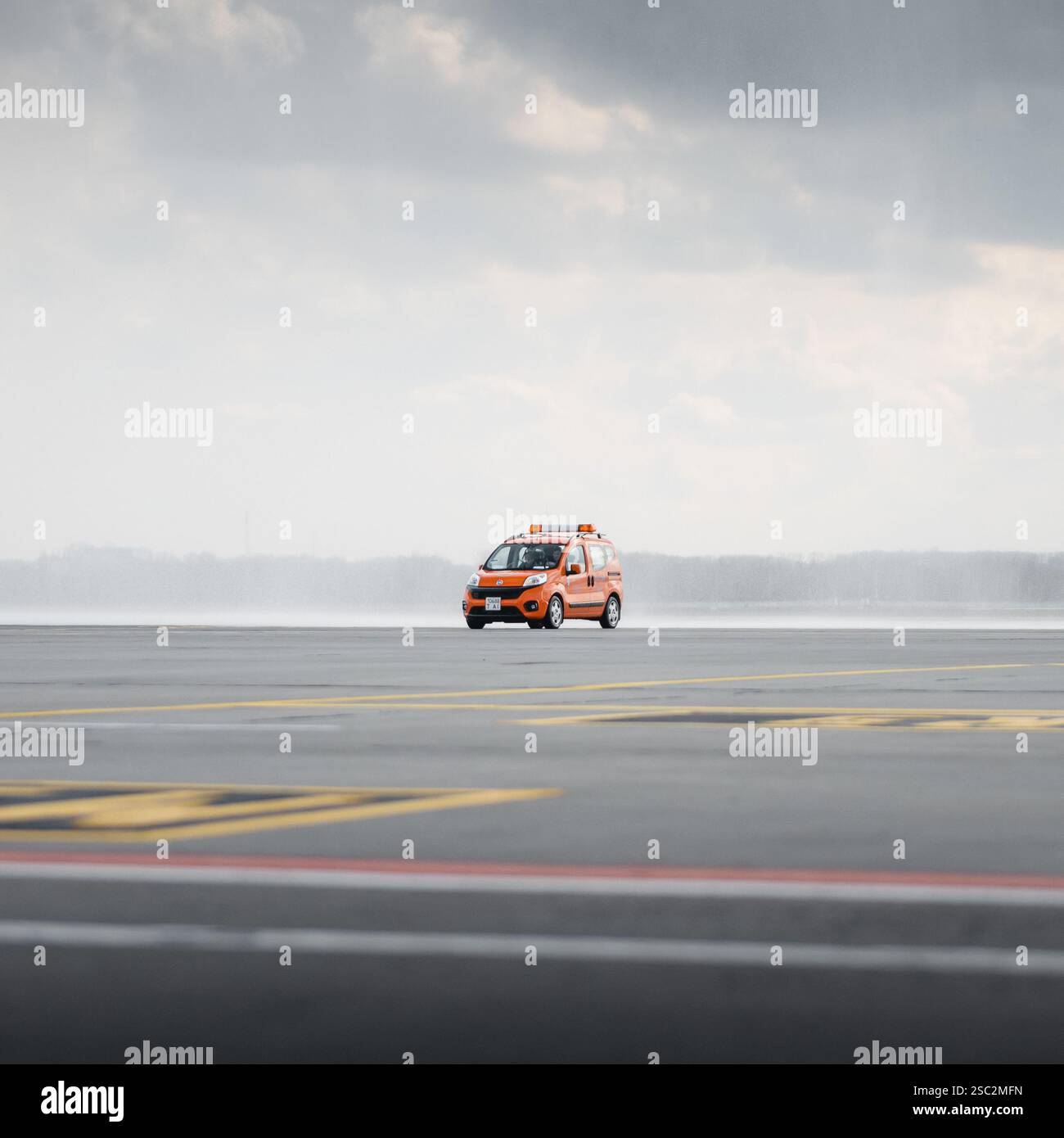 Auto arancione che mi segue all'aeroporto. Furgone FIAT con luci lampeggianti color ambra che attraversa il piazzale dell'aeroporto guidando un aereo. Foto Stock