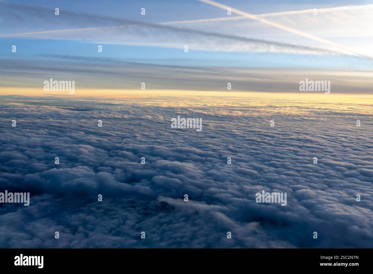 Mare di nuvole dall'alto visto attraverso l'oblò dell'aereo al tramonto Foto Stock