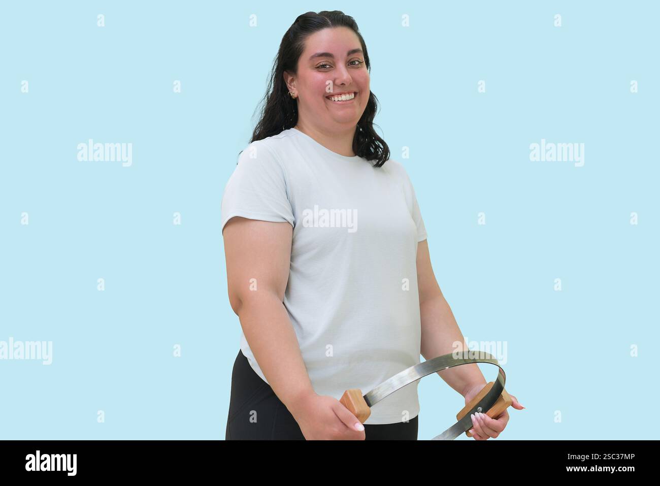 Giovane donna che posa con cerchio circolare Pilates su sfondo blu. Foto Stock