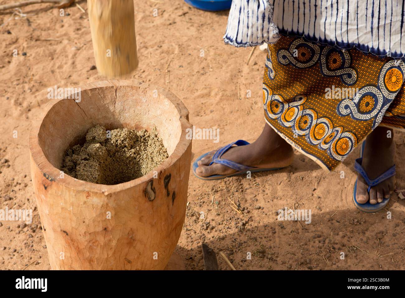 Campo Mentao per rifugiati maliani, vicino a Gibo, Burkina Faso settentrionale maggio 2012: Una donna araba sterza grano per preparare il pasto della sua famiglia. Gli arabi vivono in una sezione separata del campo. I rifugiati, per lo più Tuareg, ora sono più di 60.000 nel solo Burkina Faso, e continuano ad arrivare nei campi ogni giorno, a seguito del caos politico creato quando ufficiali militari maliani hanno inscenato un colpo di stato il 22 marzo 2012. Fotografia di Mike Goldwater Foto Stock