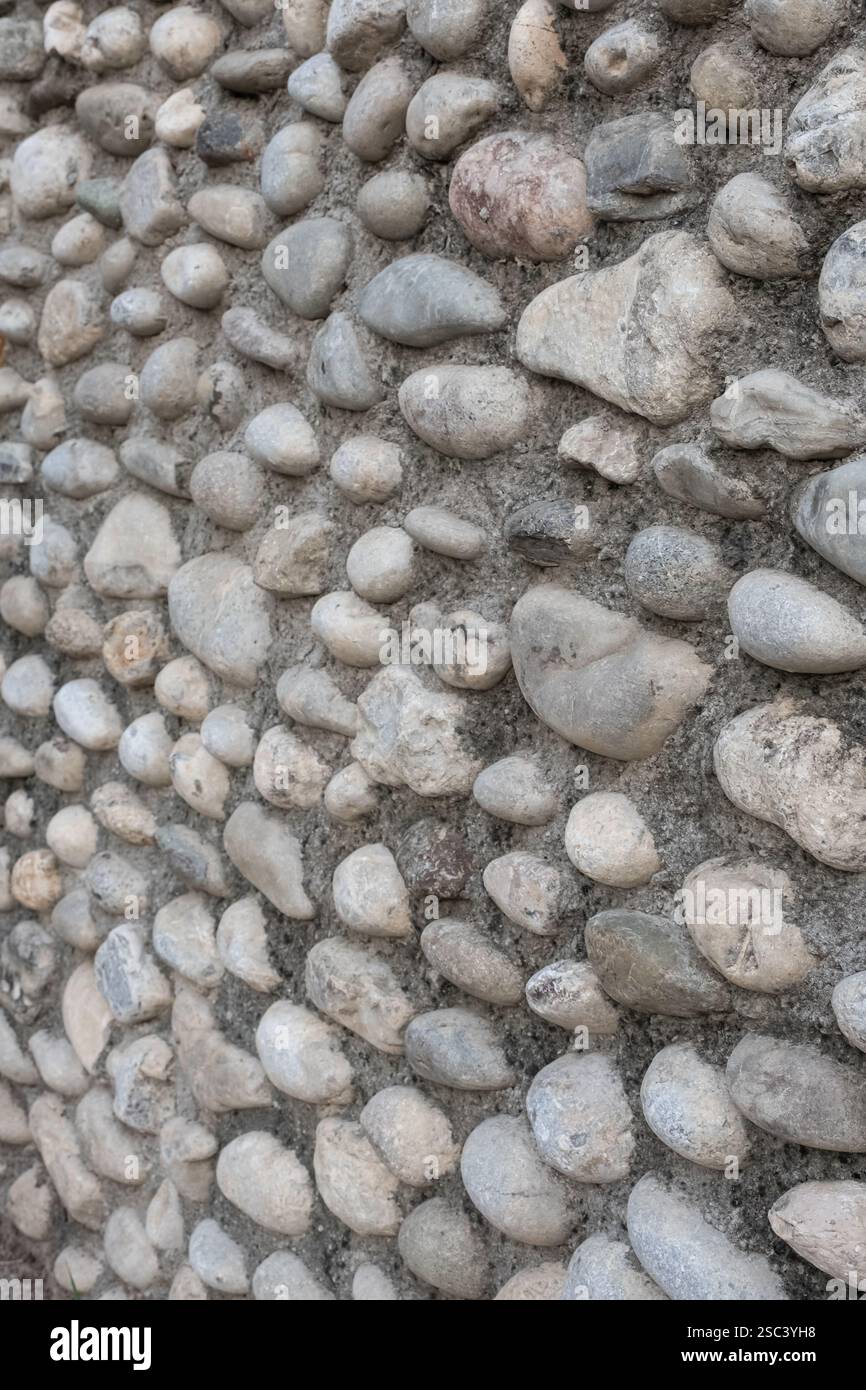 Parete esterna dell'edificio. Sfondo da parete in pietra. Tradizionale muro di pietra e fango. Muro fatto di pietre e ciottoli Foto Stock