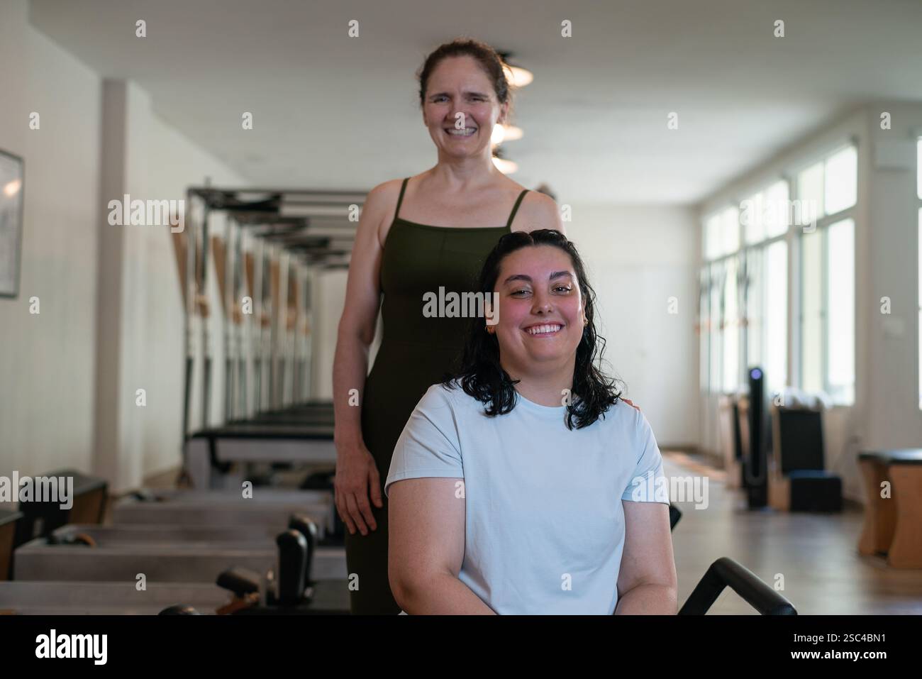 Ritratto di una giovane donna e del suo allenatore che sorride in uno studio di pilates. Foto Stock