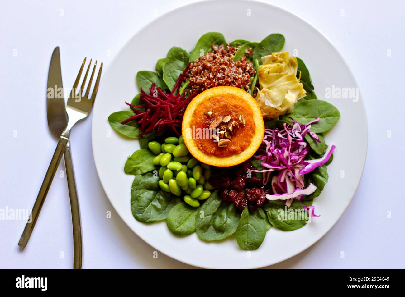 Insalata colorata composta con patate dolci all'arancia, spinaci, quinoa e verdure su sfondo bianco Foto Stock