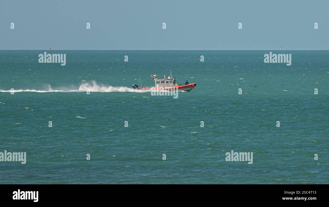 Un membro dell'equipaggio rimane aggrappato come Special Purpose Craft (forze dell'ordine) della Guardia Costiera degli Stati Uniti si muove ad alta velocità nel Golfo del Messico, nell'Oceano Atlantico Foto Stock