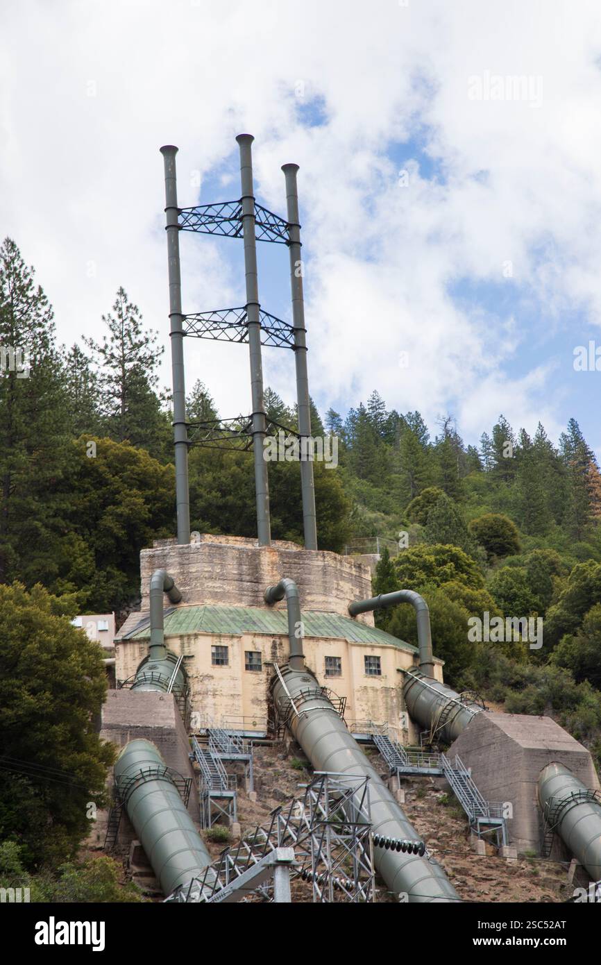 Penne industriali e alte torri di scarico presso il Pit 3 Powerhouse, un impianto idroelettrico nella contea di Shasta, California, circondato da foreste alte Foto Stock