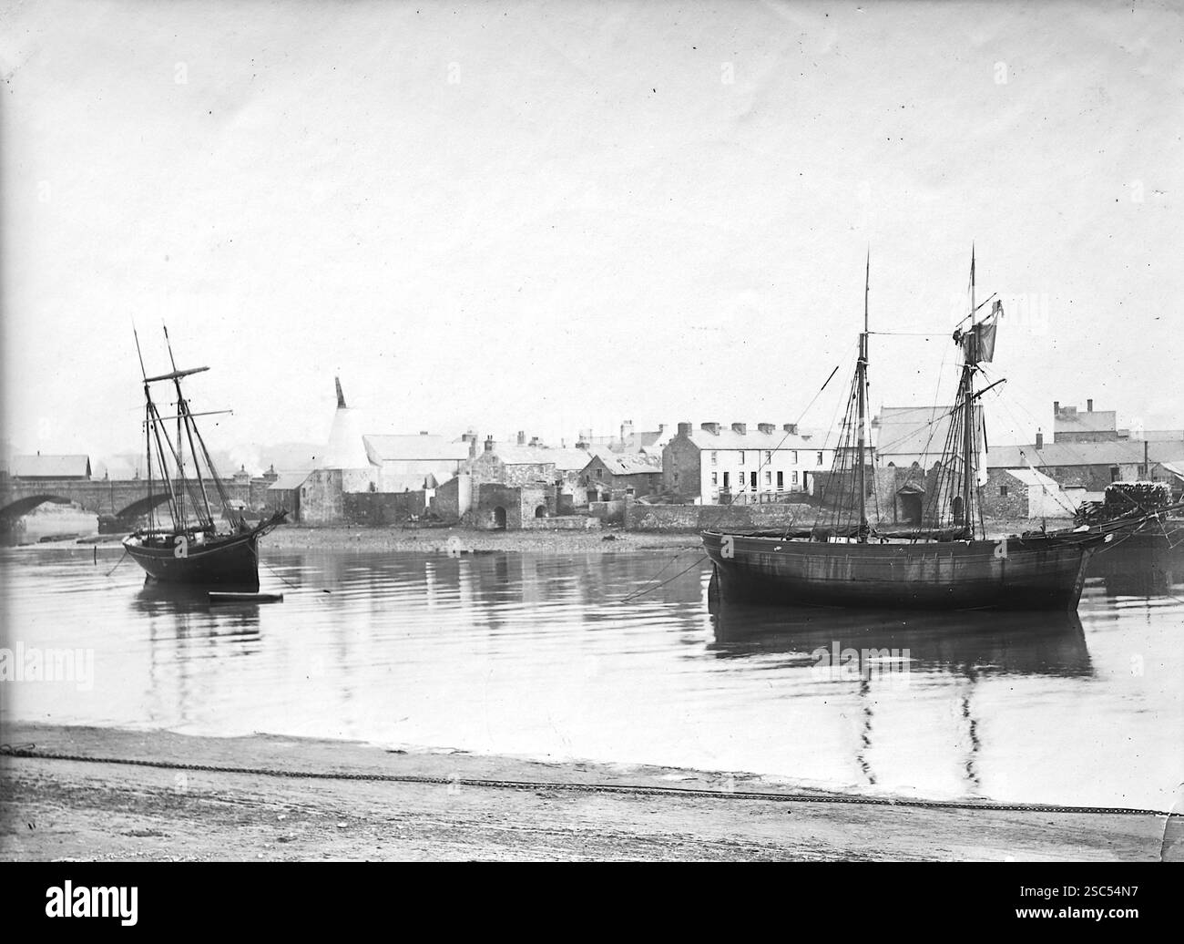 Porto con due barche in primo piano e un ponte ad arco distante, Aberystwyth, Ceredigion, Galles. 1900, monocromatico: Da un'importante collezione storica di fotografie di albumi originali, non attribuite, dal tardo Vittoriano al primo edoardiano: Un tour britannico che include Staffordshire, Warwickshire e Galles del Nord. La qualità degli originali era variabile e la maggior parte era di 108x165 mm. Foto Stock