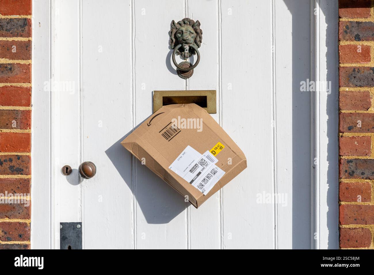 Piccolo pacchetto Amazon o pacco nella cassetta delle lettere in una porta d'ingresso di una casa, Inghilterra, Regno Unito. Concetto di shopping online Foto Stock