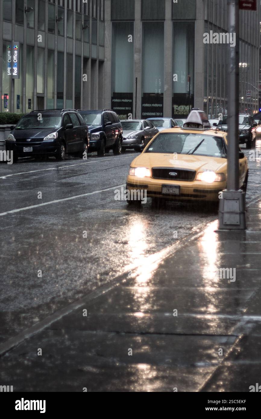 Un taxi giallo, probabilmente un taxi di New York City, percorre una strada piovosa. Foto Stock