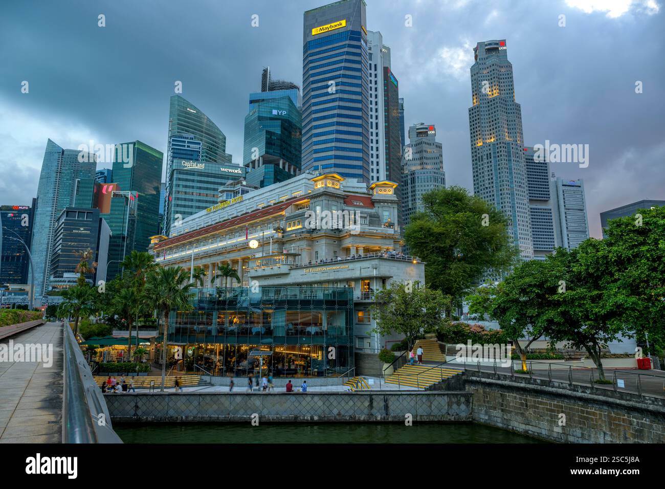 Lo storico Fullerton Hotel si trova sotto i torreggianti grattacieli del quartiere finanziario di Singapore mentre il sole tramonta sul fiume Singapore. Foto Stock