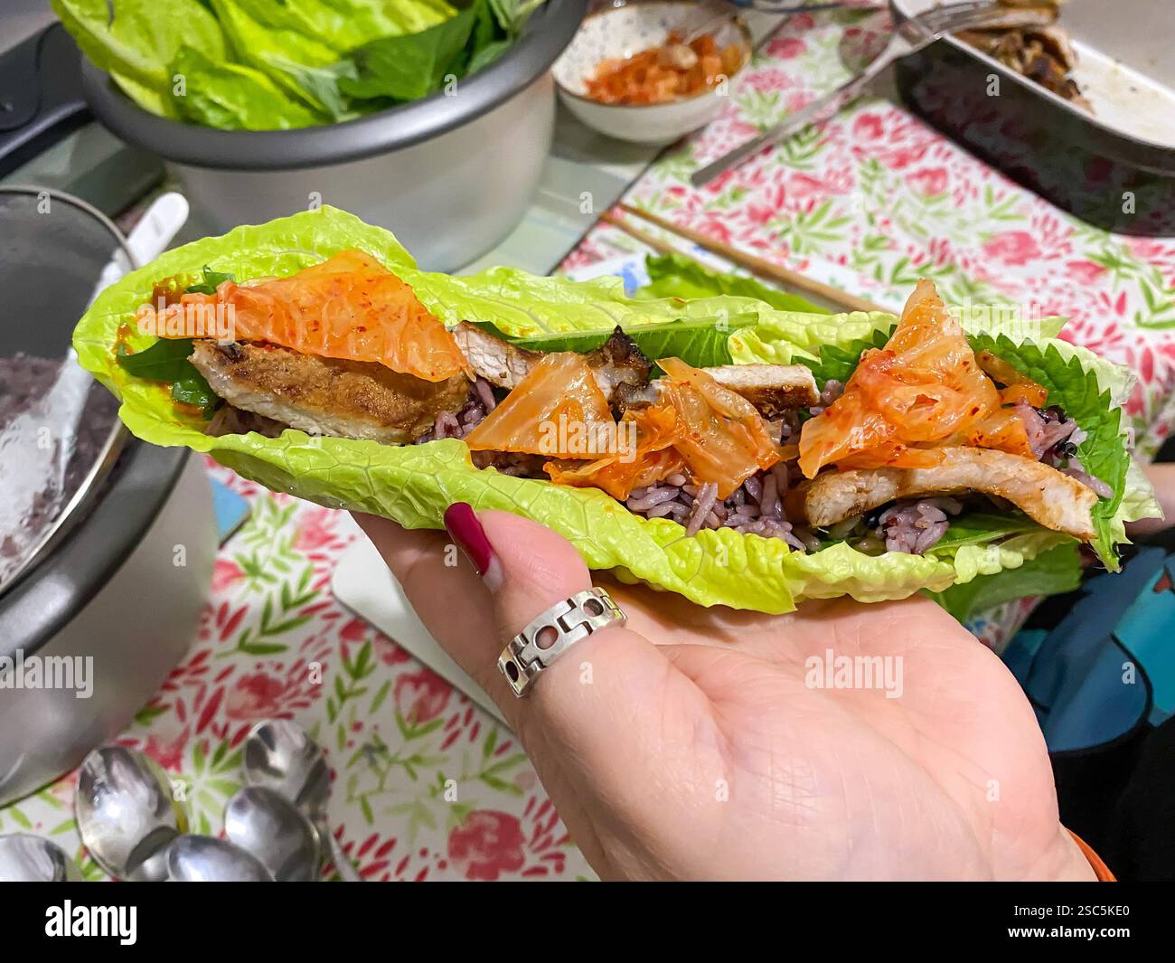 Riso, maiale alla griglia e kimchi in una foglia di lattuga romaine, un'interpretazione fatta in casa del barbecue coreano. - Immagine stock catturata con smartphone