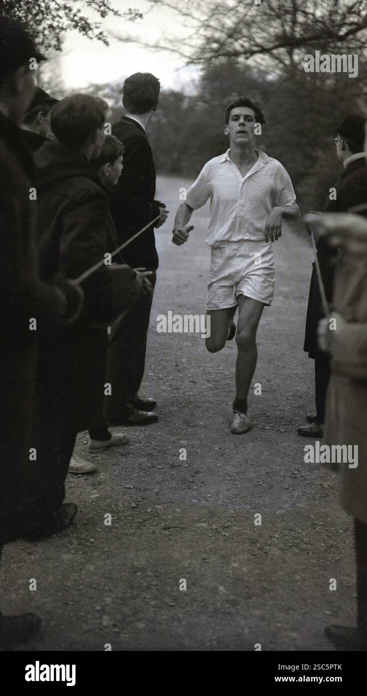 Anni '1950, storico, uno scolaro anziano che termina una gara di cross-country, compagni di alunni in attesa di tenere la corda, Oxford, Inghilterra, Regno Unito. Foto Stock