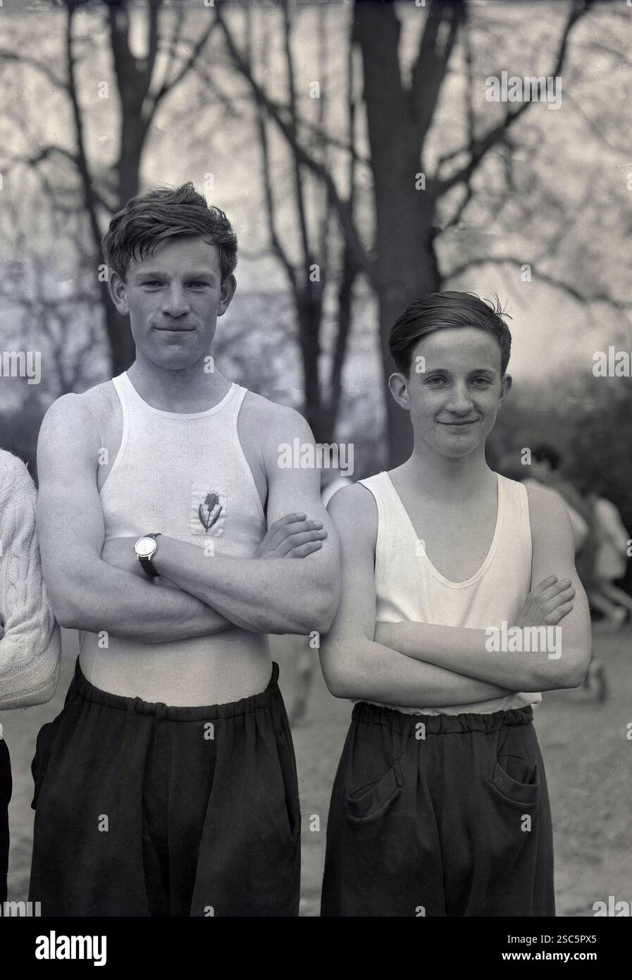 Gli anni '1950, storici, due scolari posano per una foto prima dell'inizio di una gara di cross-country, Oxford, Inghilterra, Regno Unito, entrambi con indosso il canottiere o il giubbotto da corsa tradizionale. Foto Stock