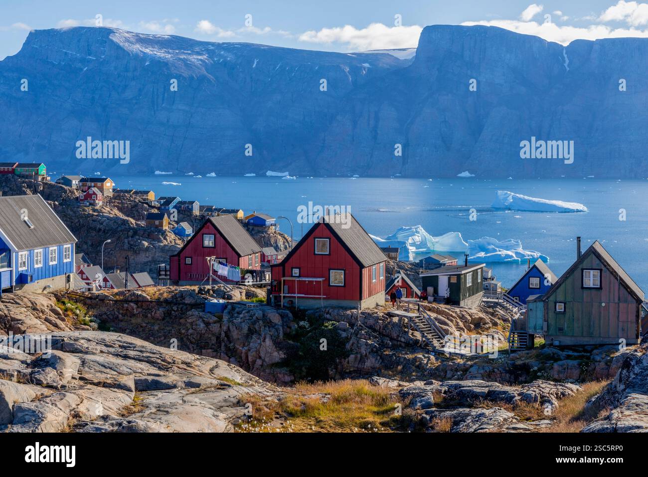 Case di Colourfullhouse costruite su rocce con vista sul fiordo di Uummannaq, gli iceberg e la costa opposta con le sue montagne. Uummannaq, Groenlandia, Danimarca Foto Stock